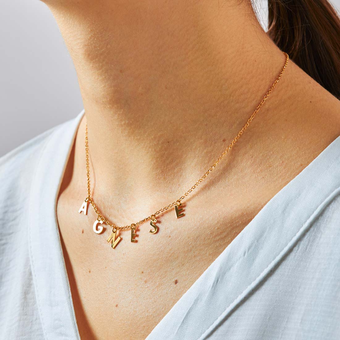 Collana con nome formato da lettere pendenti, indossata nella versione placcata oro
