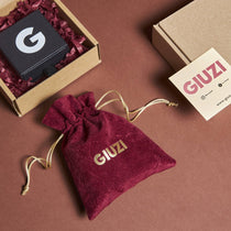 Confezione regalo composta da sacchettino in velluto amaranto con logo GIUZI oro, scatolina nera e tutto contenuto in una scatola di cartone riciclato.